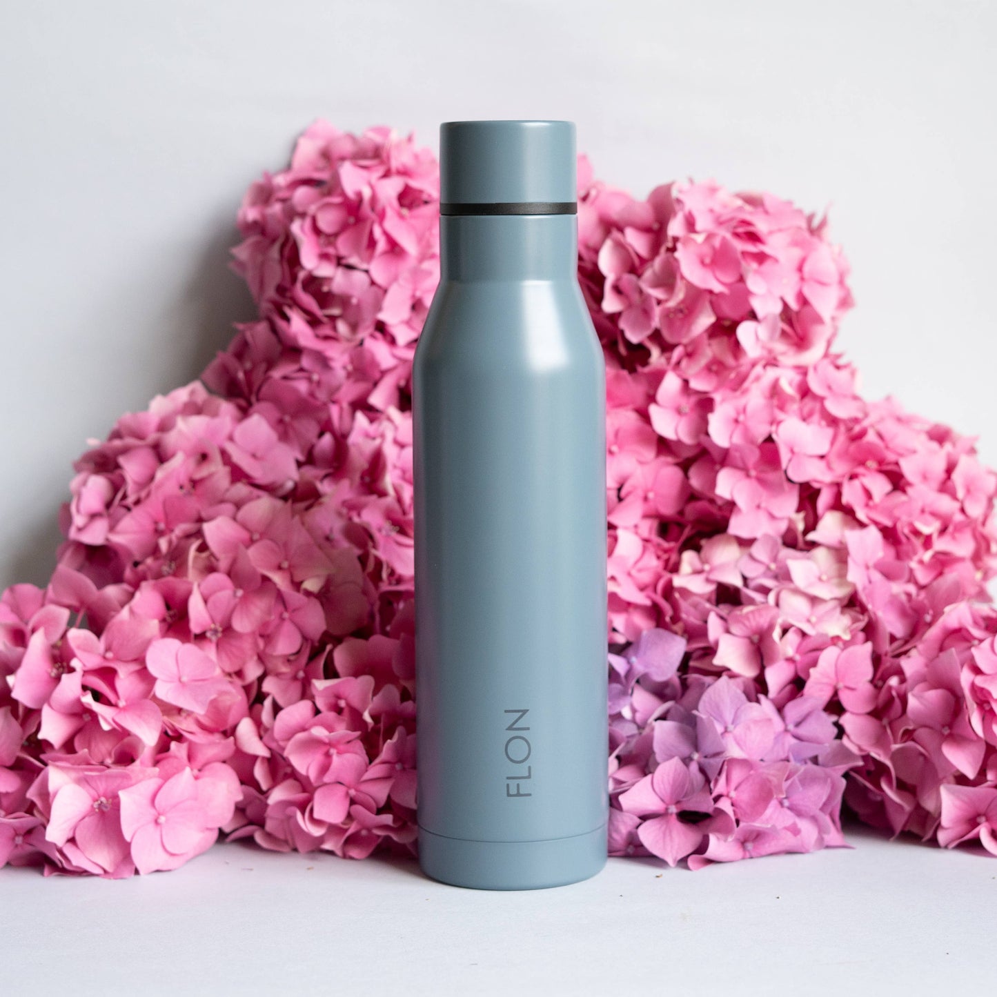 Gray water bottle with black lid on pink flowers