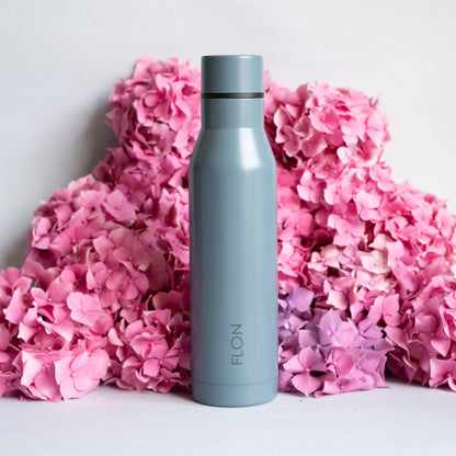 Gray water bottle with black lid on pink flowers