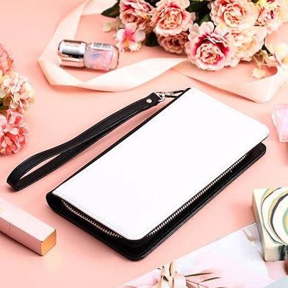 White clutch bag with black strap on a pink surface with flowers and lipsticks.