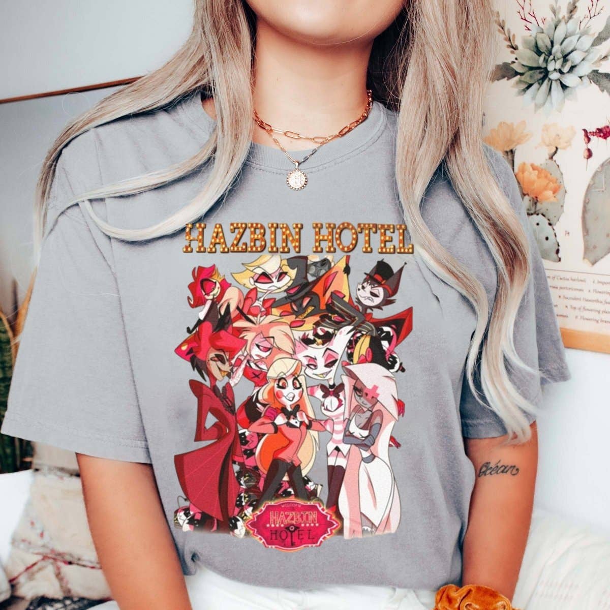 Person wearing a gray t-shirt with 'Hazbin Hotel' character design.