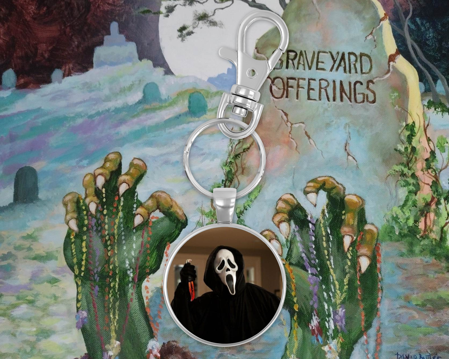 Keychain with Ghostface design on a colorful background resembling 'Graveyard Offerings' album cover.