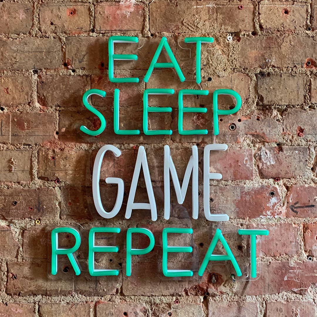 Neon sign with 'Eat Sleep Game Repeat' text on a brick wall