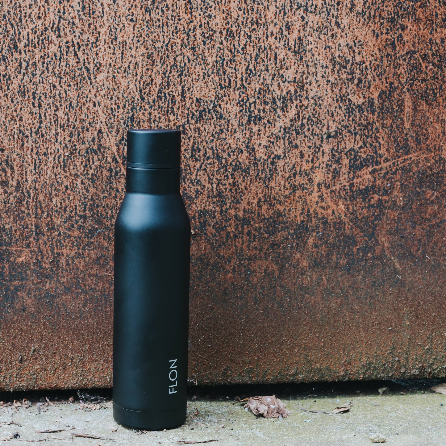 Black water bottle with 'ELON' branding against a textured brown background