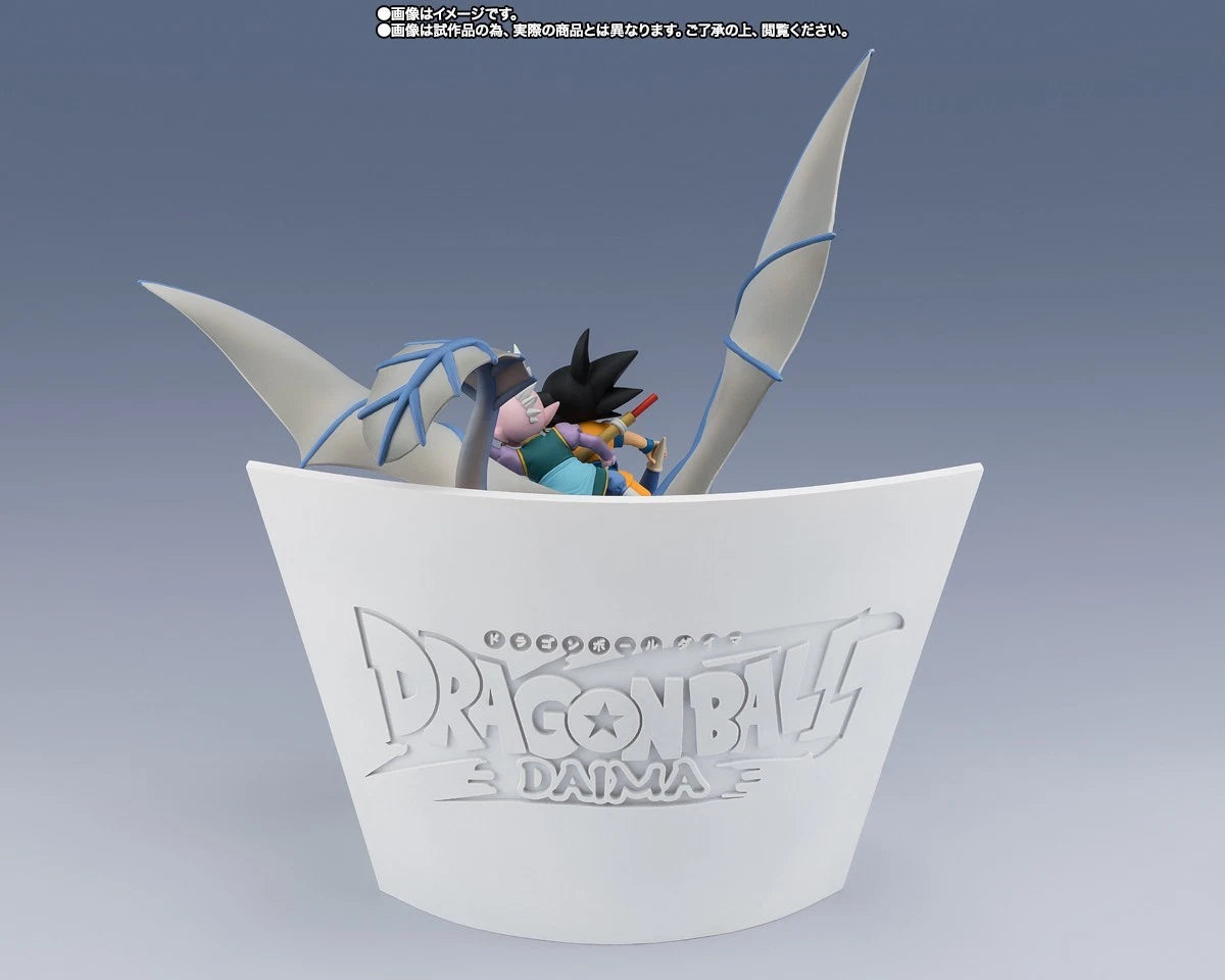 Dragon Ball Z Daima figure display stand featuring Goku and Vegeta in a cup-like base with Dragon Ball Z Daima branding, shown on a blue-gray gradient background.